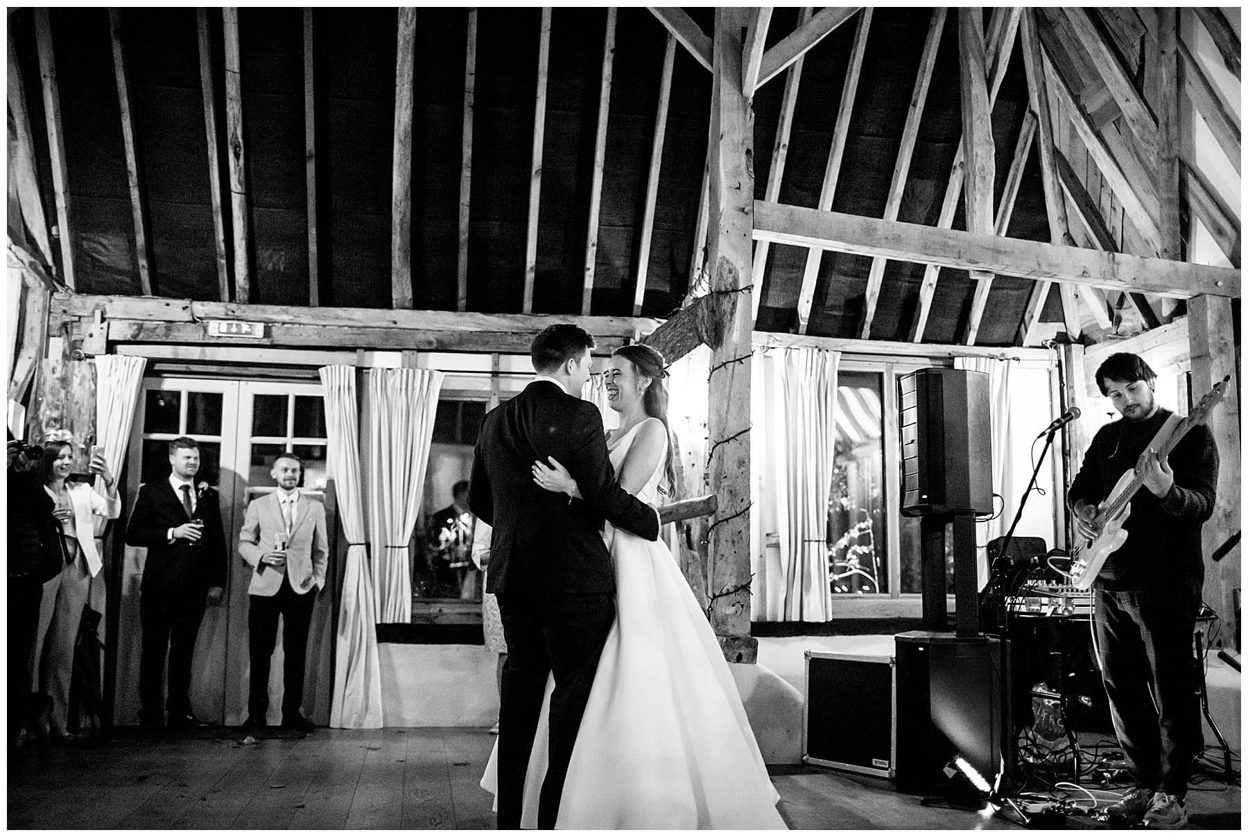 bride and groom having their first dance together at their cosy rainy day Clock Barn wedding
